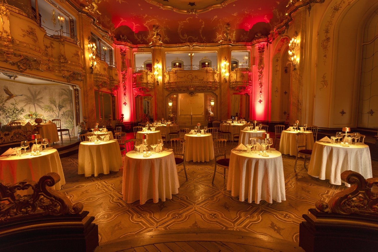 A large room filled with dining tables, with a scene in the background featuring light and red