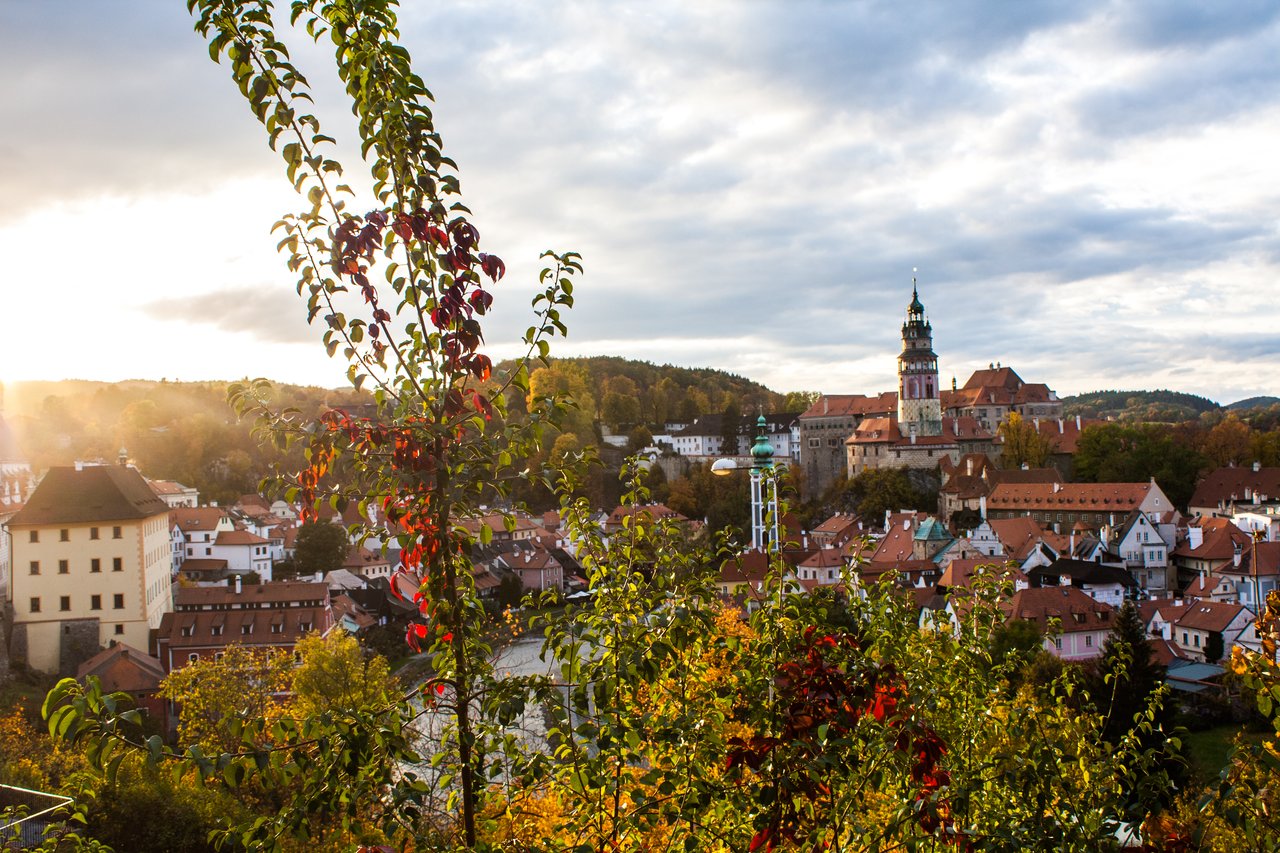 A bird's-eye view of the rooftops of life with a grand castle on a hill, under a sunset