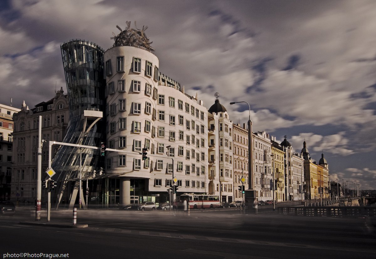 The cream-white facade of a building, with another glass building leaning against it