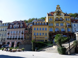 en:a street lined with colorful buildings; a statue in the middle of the square, with stairs ;fr:une rue bordée de bâtiments colorés ; une statue au milieu de la place, avec des escaliers