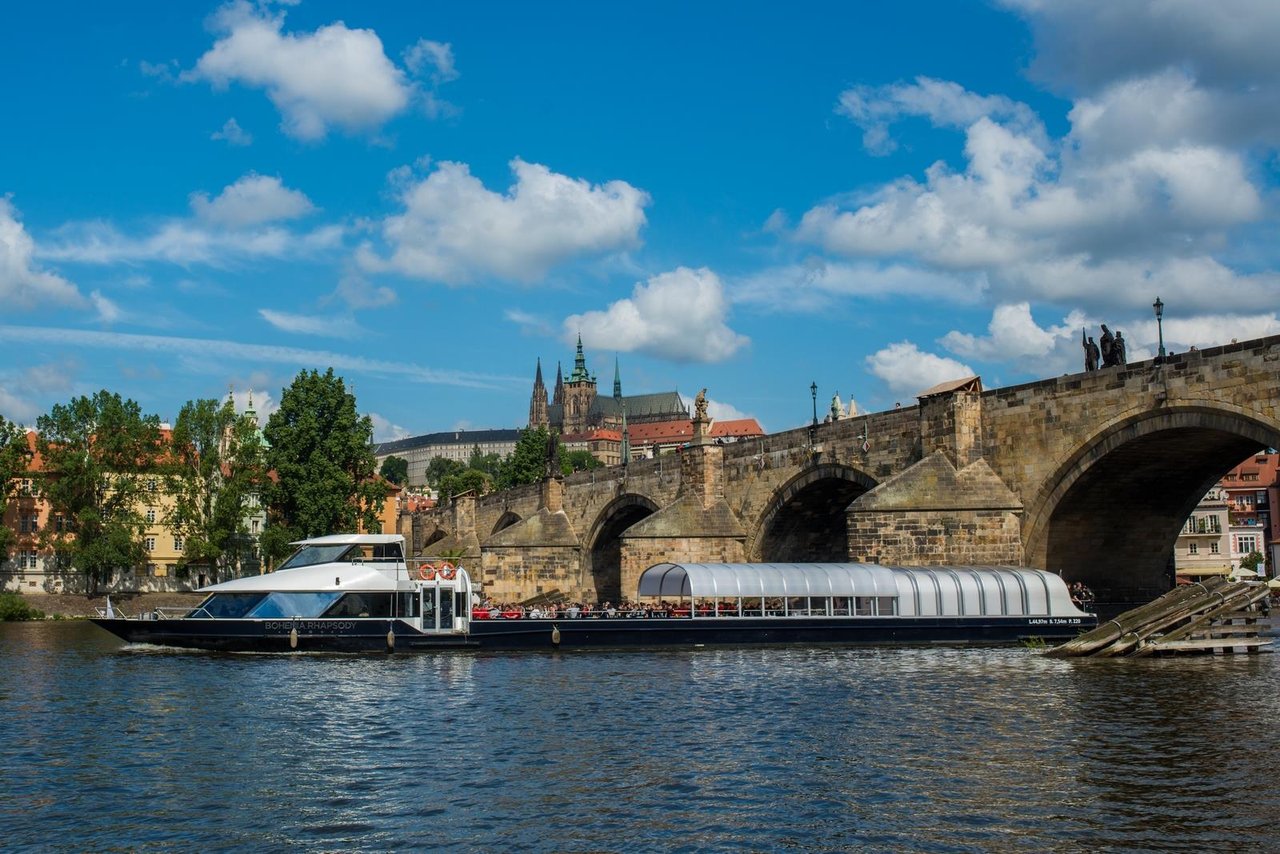 A large boat passing under a bridge with its roof half-open