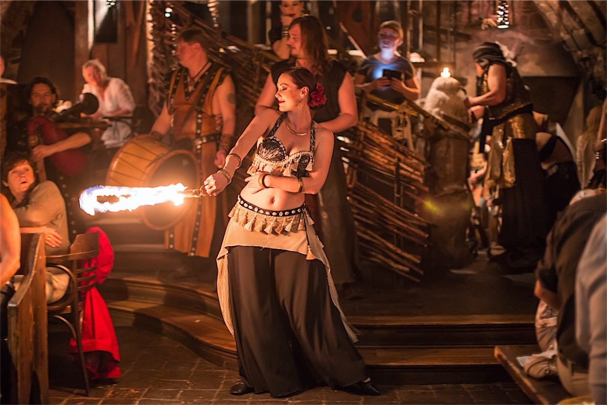 A woman in medieval costume dancing with a large burning ship—the audience is surprised