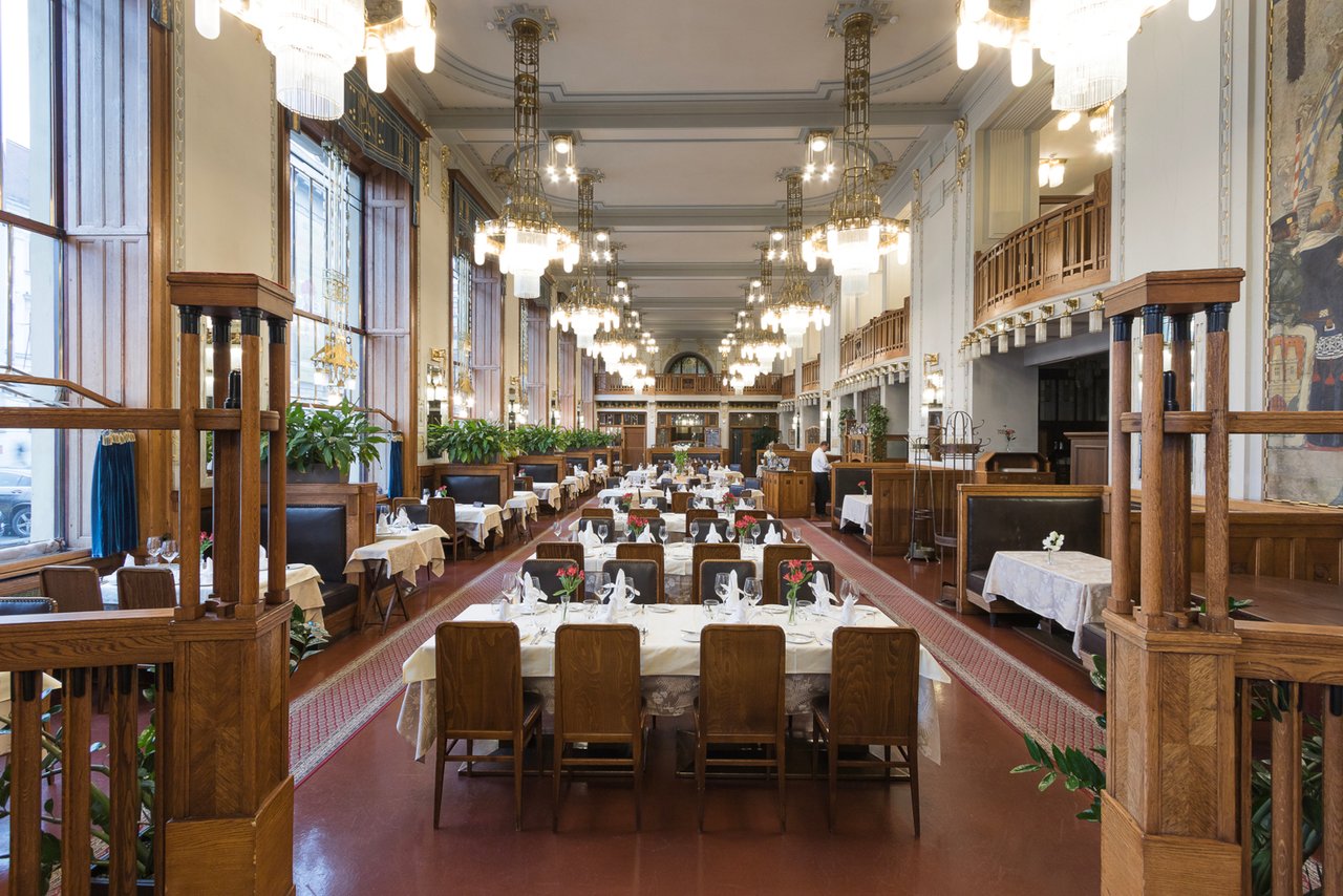 A long row of tables with chandeliers hanging from the ceiling