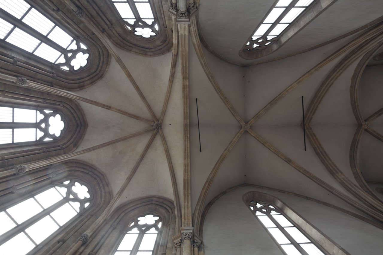 Very high stone ceiling with stained glass windows on the sides